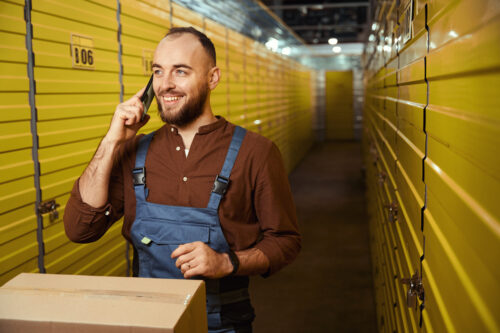 Pleasant young man talking on mobile phone with self-storage tenant